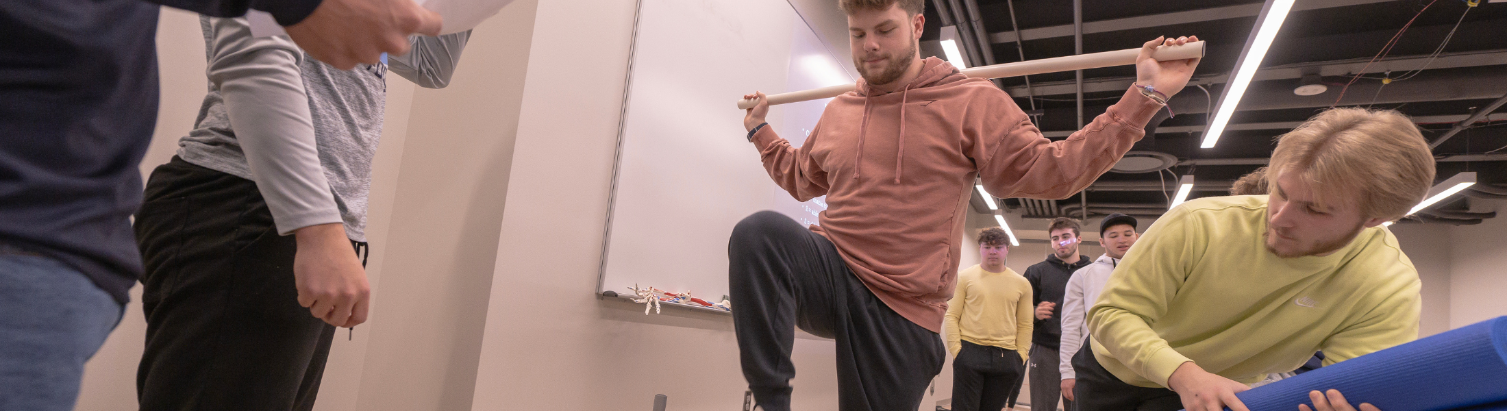 group of students watch another student completing an exercise science task