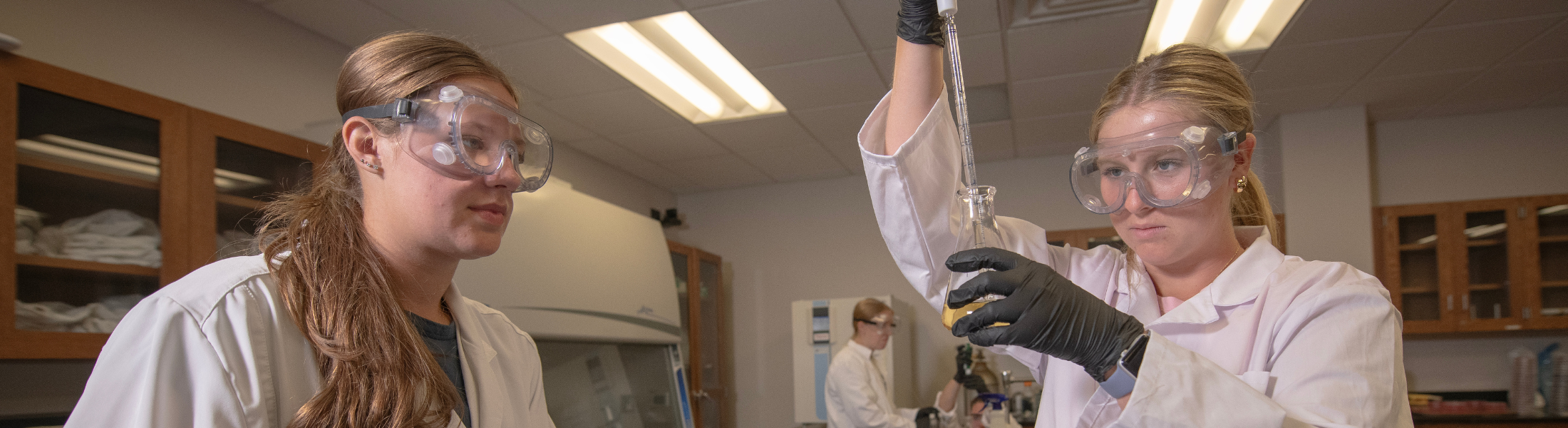 two students concentrating on beaker