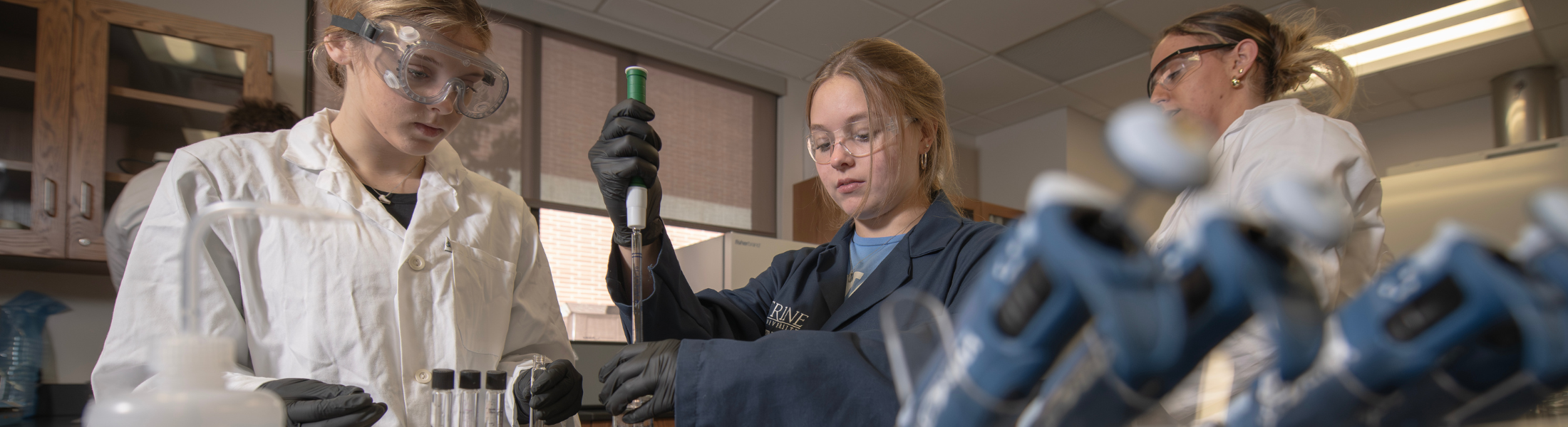 three students practicing a chemical experiment