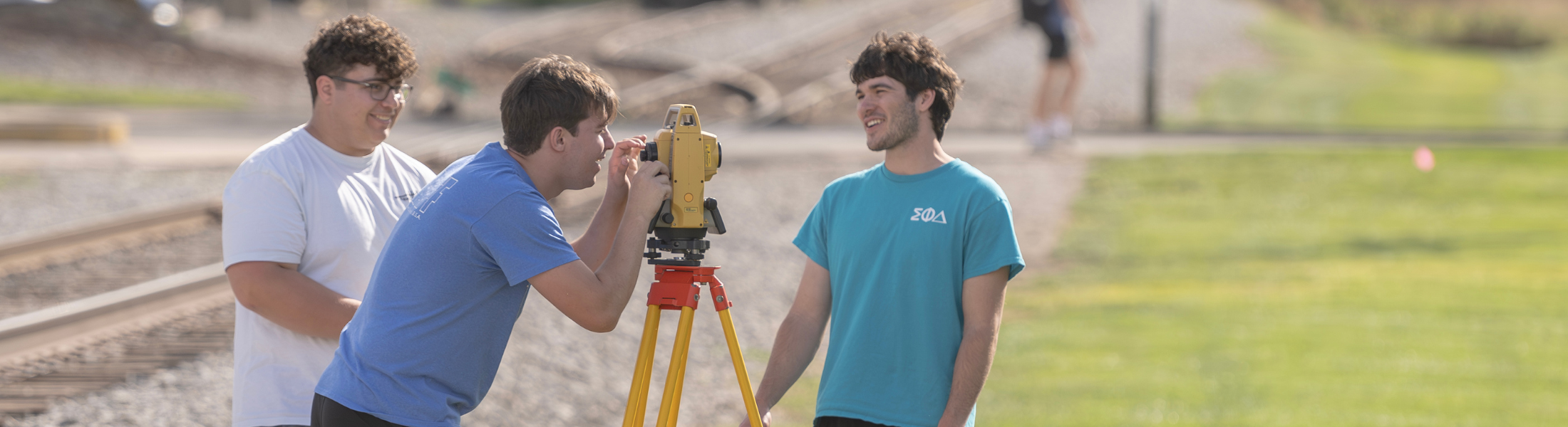 trine students using surveying equipment on campus