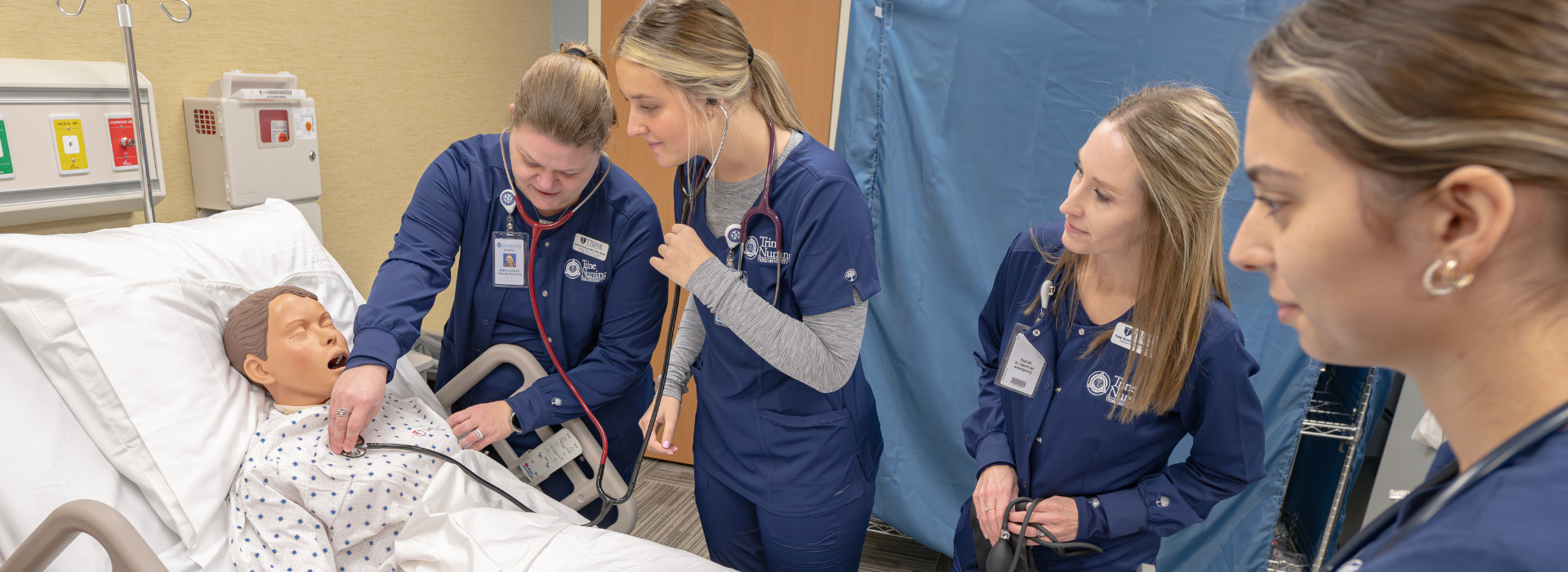 trine nursing students learn on a practice patient