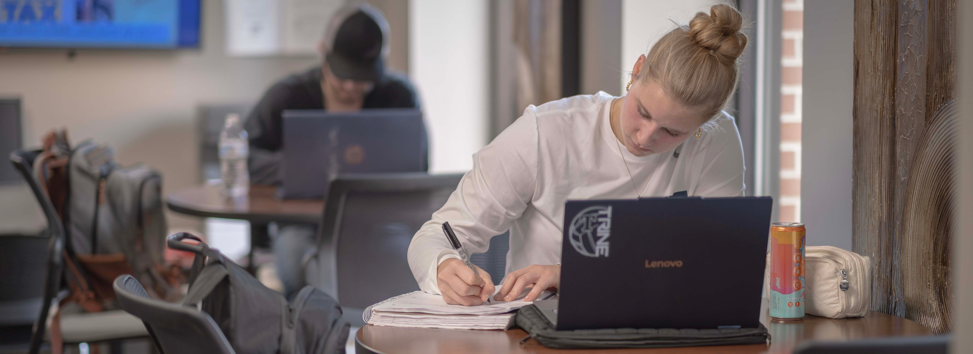 student taking notes on a notebook while studying alone
