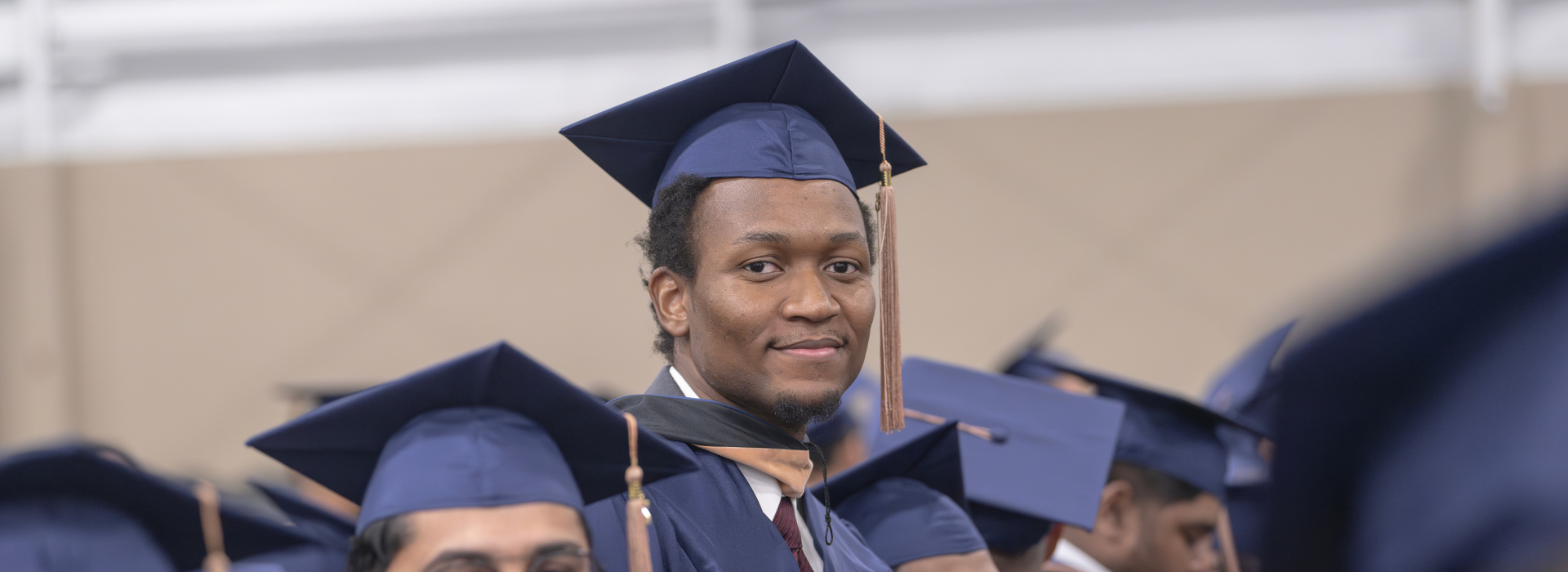 student smiling in a graduation regalia during commencement