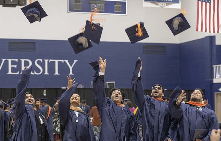 Graduates tossing caps into the air