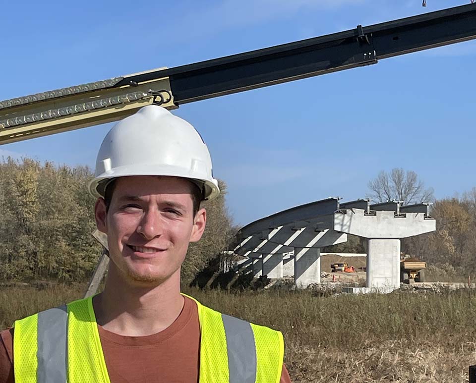 Trine University civil engineering student in front of bridge construction