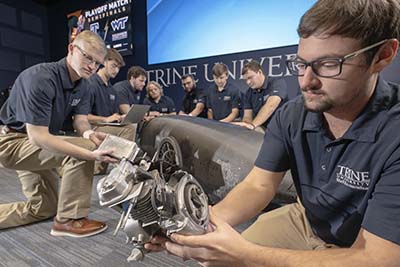 Trine University Eco-marathon students with vehicle and parts
