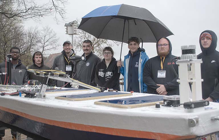 Students standing behind low-profile vessel