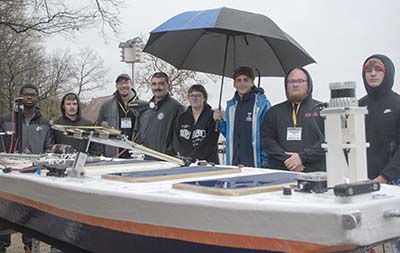 Students standing behind low-profile vessel