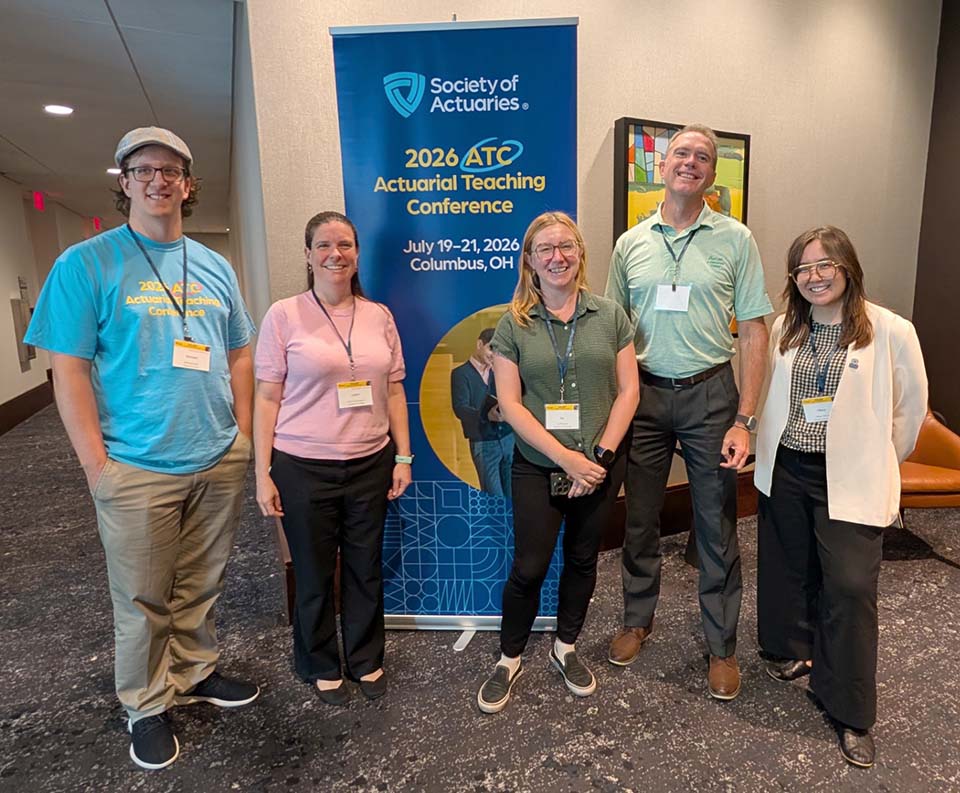 Group of five people in front of conference banner