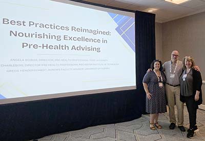 Three people standing next to large presentation screen