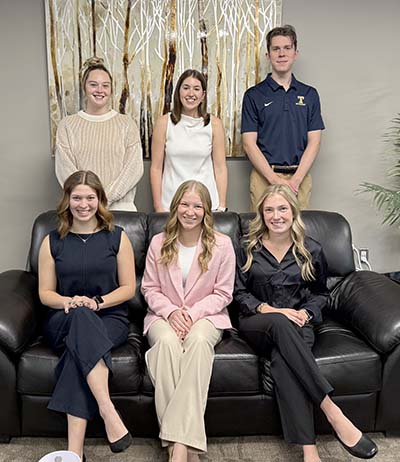 Three students seated on couch with three students standing behind them