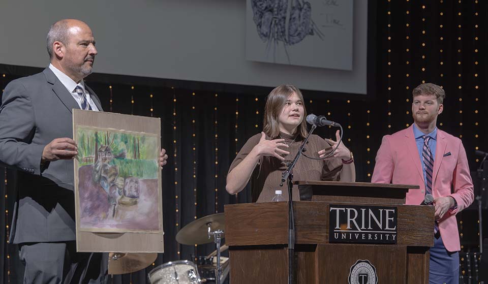 Trine student Adela Les speaks with Cisco Ortiz holding her painting