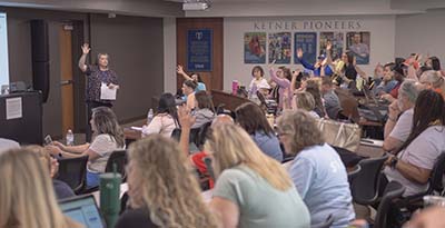People in classroom raising hands
