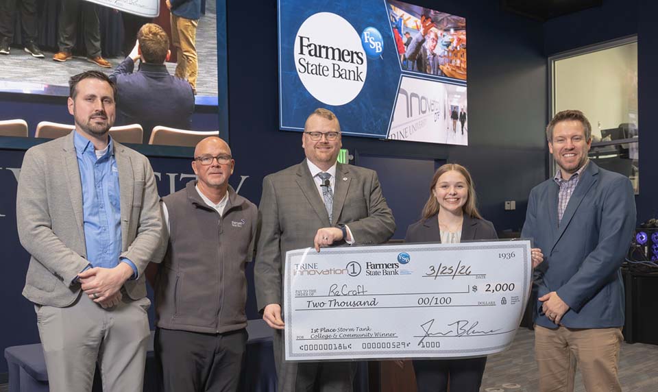Three bank executives and one college administrator presenting large check to student.